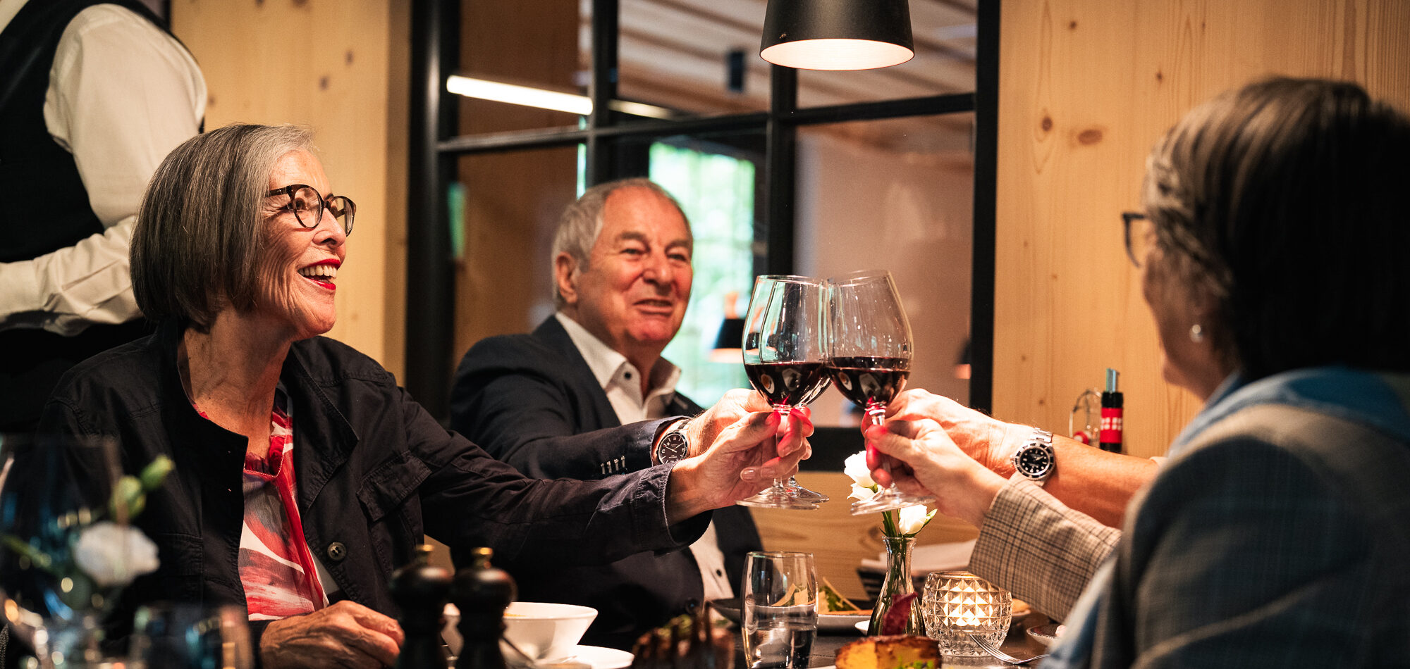 Gäste stossen bei einem Abendessen mit Rotwein an – Hotel Arc-en-ciel Gstaad