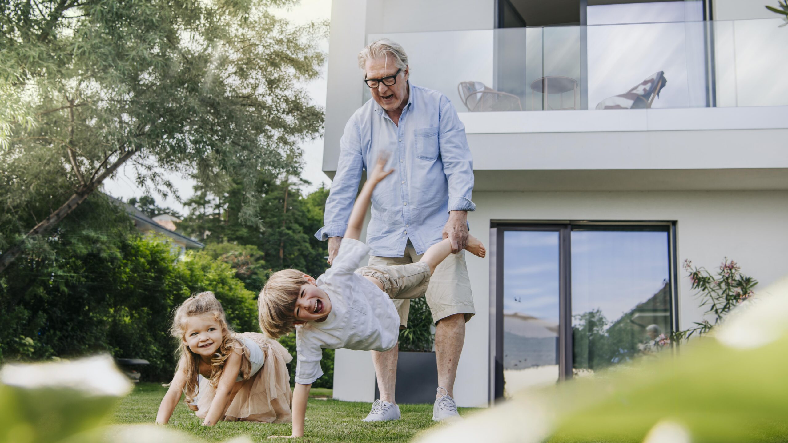 Familie spielt mit Hund im Garten – B+G Schweiz Key Visual