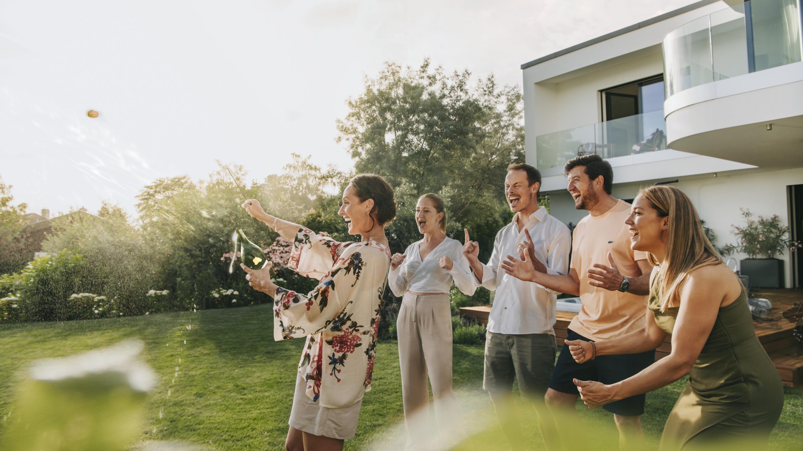 Gruppe geniesst einen Gartenabend bei einem modernen Haus – B+G Schweiz Key Visual